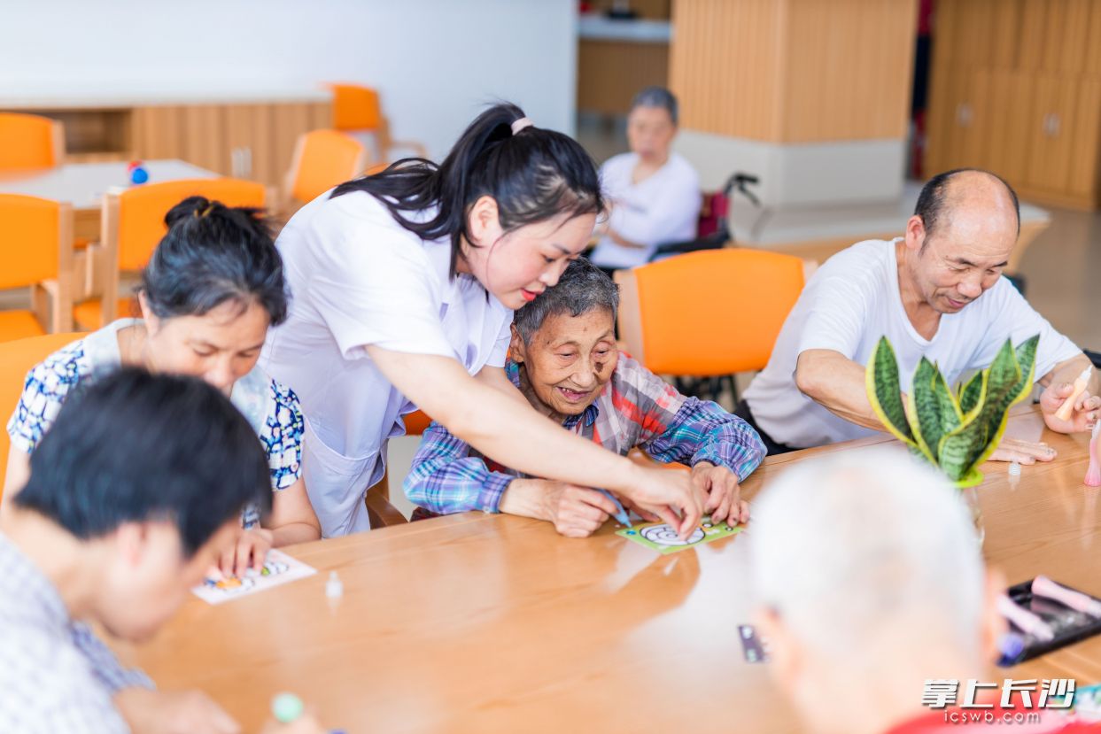 天心区社会福利中心员工帮助老年人做手工益智活动。通讯员 莫坤 供图